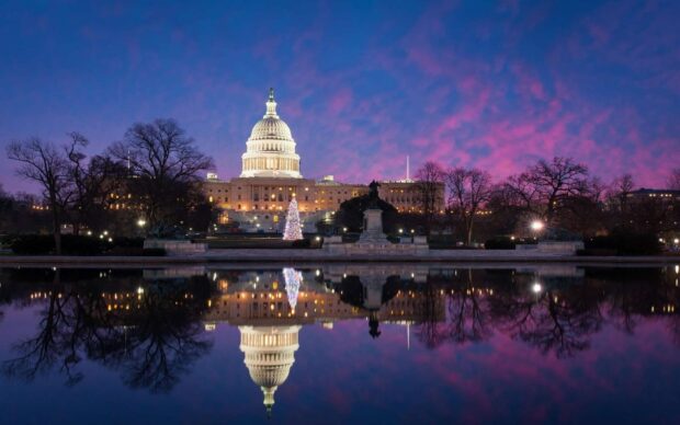 The United States Capitol building of Washington Dc at dusk with colorful sky and reflective water surface
