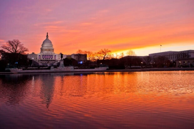 The United States Capitol building reflecting on the water during a vibrant Washington Dc sunset