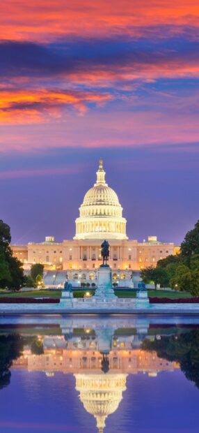 The United States Capitol building in Washington Dc during sunset with beautiful sky colors reflected in water