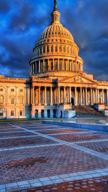 The Capitol building in Washington Dc is illuminated under a dramatic sky