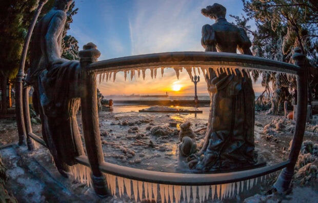 Frozen statues and icicles covered in frost during a winter sunset scene