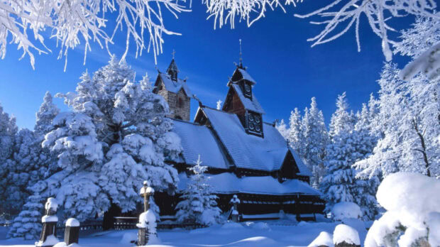 Snowy winter landscape with snowy trees and a wooden church covered in snow