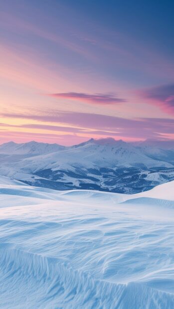 Winter landscape with snow covered hills and mountains under a colorful sky at sunset
