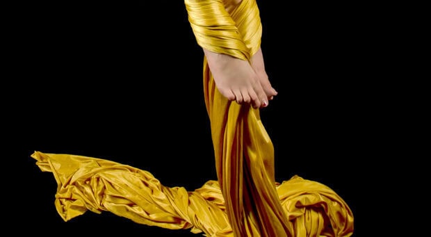 Feet wrapped in yellow aerial silks fabric performing aerial silks