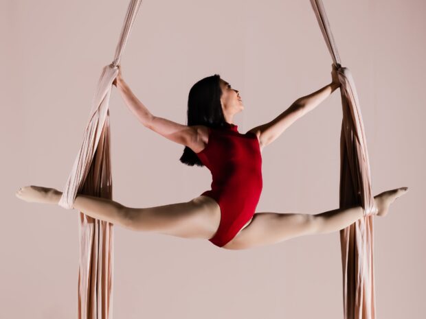 Aerial silks athlete performing a split while suspended in fabric