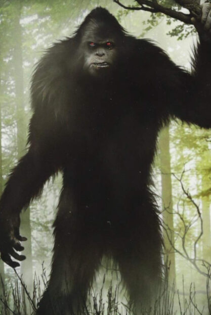 A dark Bigfoot standing in a misty forest with glowing red eyes