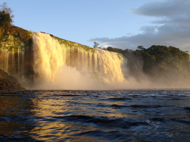 Waterfall at Canaima National Park with lush green trees and flowing river during sunset