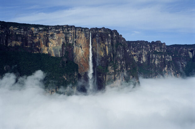 Waterfall flowing from cliffs in Canaima National Park surrounded by fog and forest