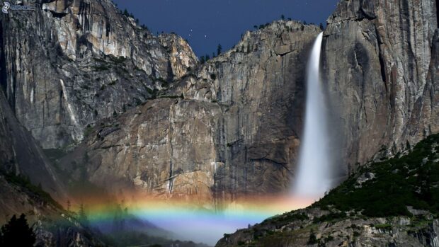 A waterfall in Canaima National Park with a vivid rainbow appearing at the base of the cliffs