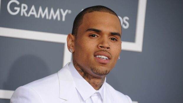 Chris Brown smiling in a white suit at the Grammy Awards event