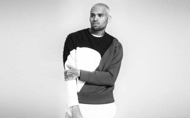 Chris Brown standing with folded arms wearing a color block sweater