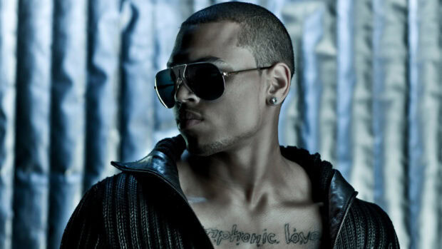 Chris Brown with sunglasses and tattoo looking sideways in stylish attire