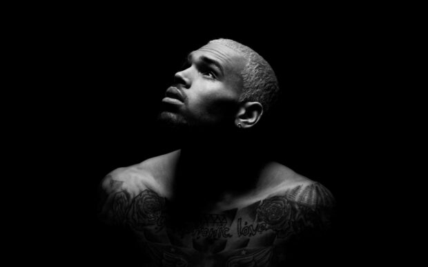 Chris Brown showing his tattoos and platinum blonde hair in a dramatic black and white portrait