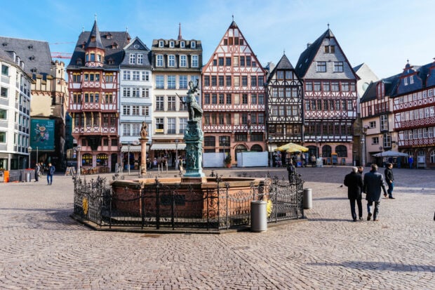 Historic city square with traditional buildings and a detailed fountain in the center