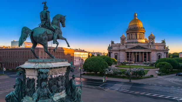Equestrian statue in the city square near a historic building with golden dome