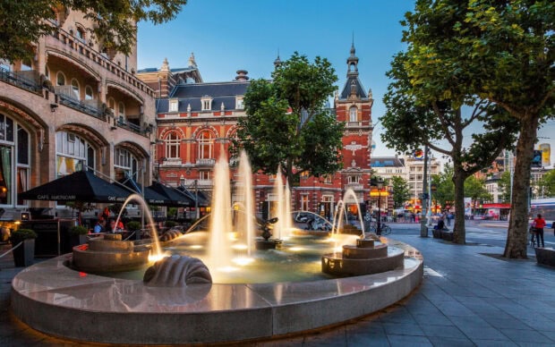 Historic city square with illuminated fountain and European architecture in the evening