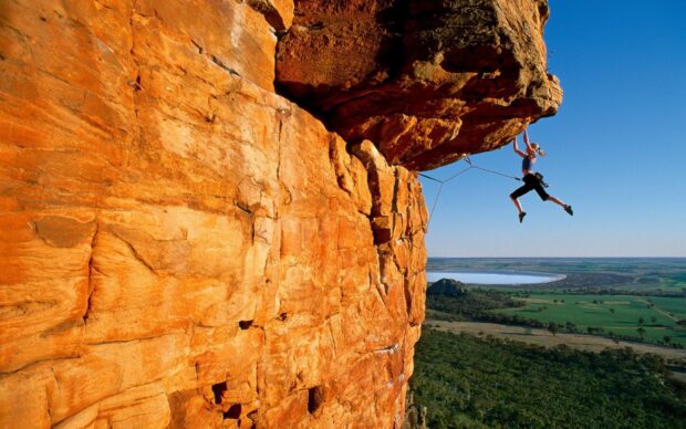 Female climber hanging from a rock face on a challenging climbing route