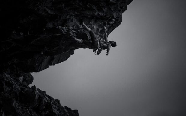 A man practicing climbing on a steep rocky cliff in a challenging outdoor setting