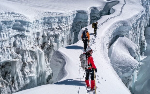 Experienced climbers traversing a snowy mountain ridge during a high altitude expedition