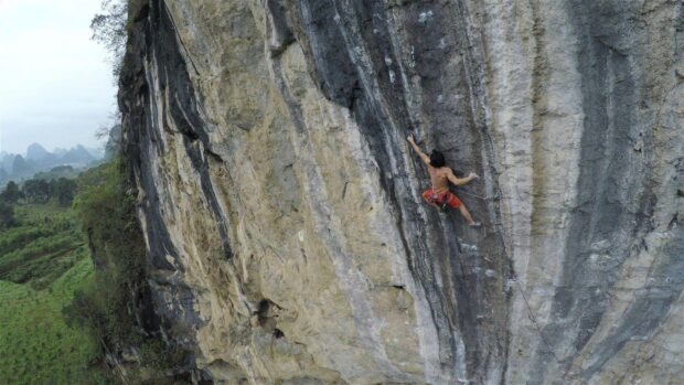 A climber scaling a steep rock face showing climbing skills and strength
