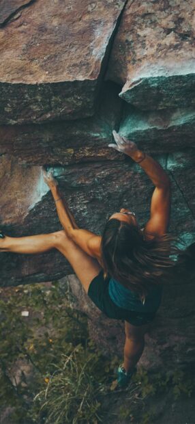 Woman climbing a steep rock face showing strong climbing technique