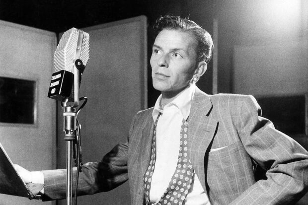 Frank Sinatra in a vintage studio recording session wearing a suit and patterned tie