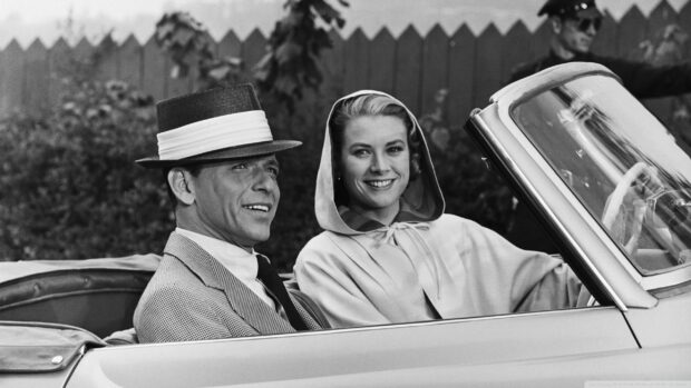 Frank Sinatra sitting in a car with a smiling woman in a classic black and white scene