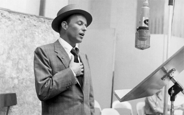 Frank Sinatra performing in a recording studio with a microphone and music stand