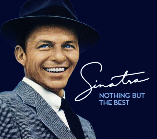 Frank Sinatra smiling in a suit and hat with bright blue eyes and a dark background