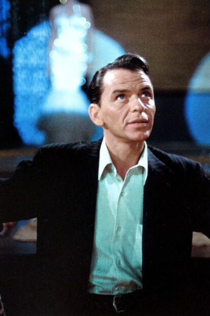 Frank Sinatra wearing a black suit and white shirt looking upward in a classic setting