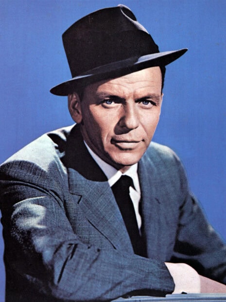 Classic portrait of Frank Sinatra wearing a hat and suit with a blue background