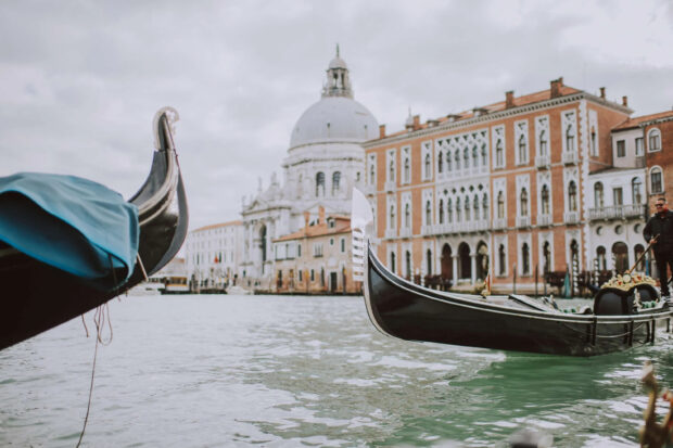 The iconic gondola boat floating on Venice canal near historic buildings and church dome