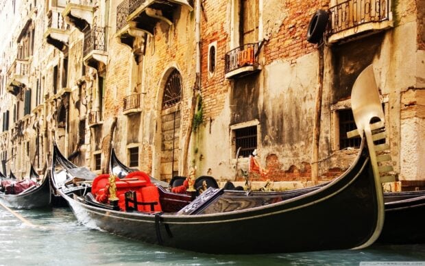 Traditional gondola floating on a canal next to old brick buildings in Venice