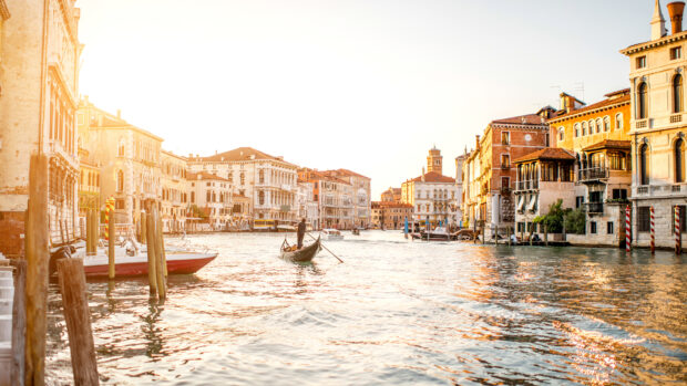 A gondola gliding through a sunlit canal lined with historic buildings in Venice