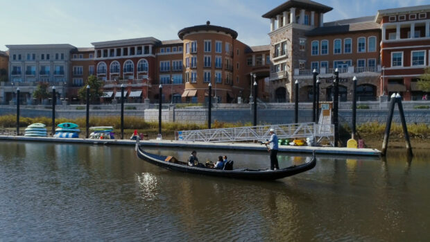 A gondola carrying passengers glides smoothly on the water near urban buildings in the city