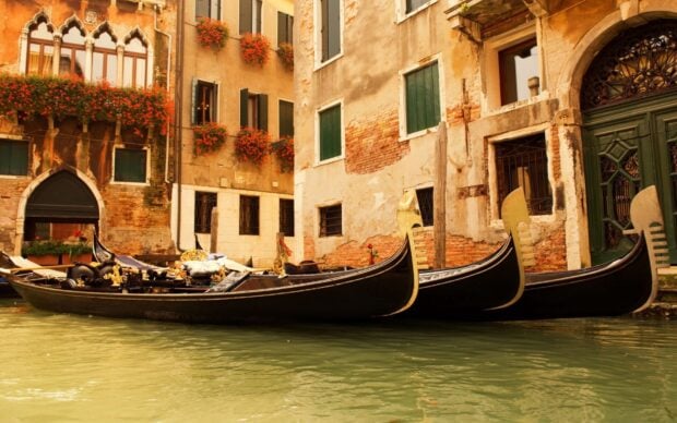 Traditional gondola resting on a canal with historic buildings in Venice Italy
