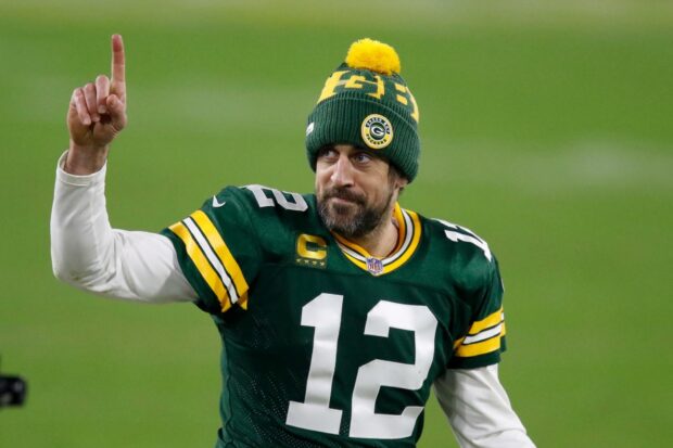 Aaron Rodgers wearing Green Bay Packers gear and pointing upward on the field