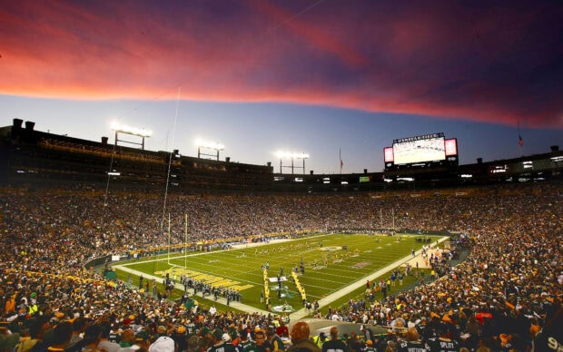 A vibrant Green Bay Packers football game at sunset with fans filling the stadium
