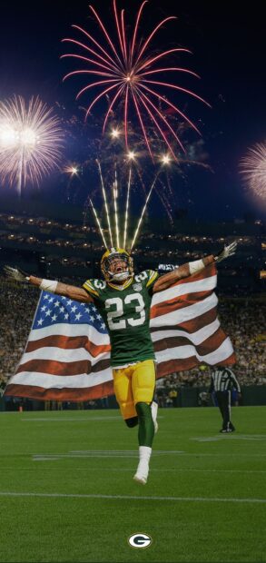 Green Bay Packers player celebrating with American flag and fireworks in stadium night