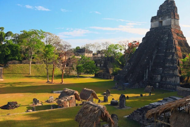 Ancient archaeological site with Guatemala ruins and lush greenery under blue sky