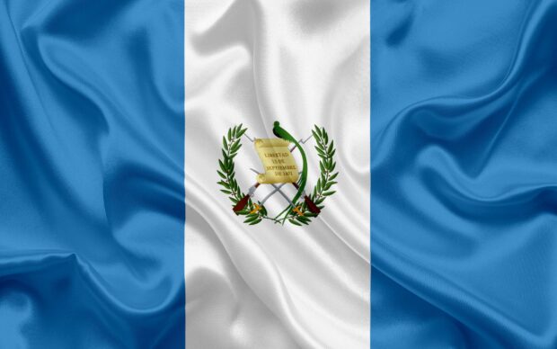 The Guatemala flag with a detailed coat of arms waving gently on a silky fabric background