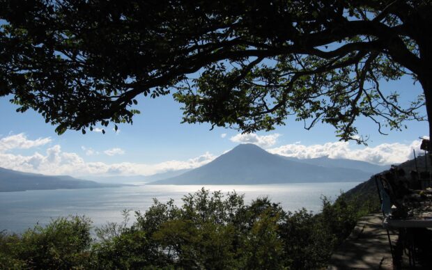 Volcano landscape framed by tree branches over Lake Atitlan in Guatemala