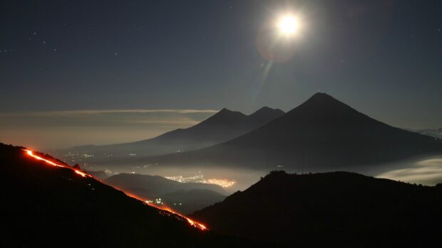 Active volcano with glowing lava flowing down the slope in Guatemala at night
