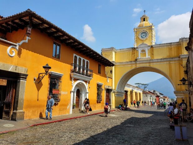 The colonial street with yellow arch and volcanic mountain in Guatemala cityscape