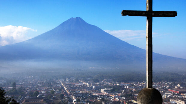 View of Guatemala city with a volcano and a stone cross in the foreground