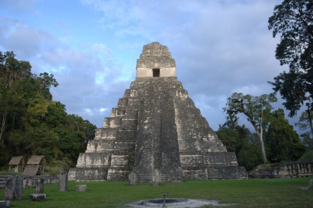 Ancient Maya temple in Guatemala surrounded by lush forest and blue sky