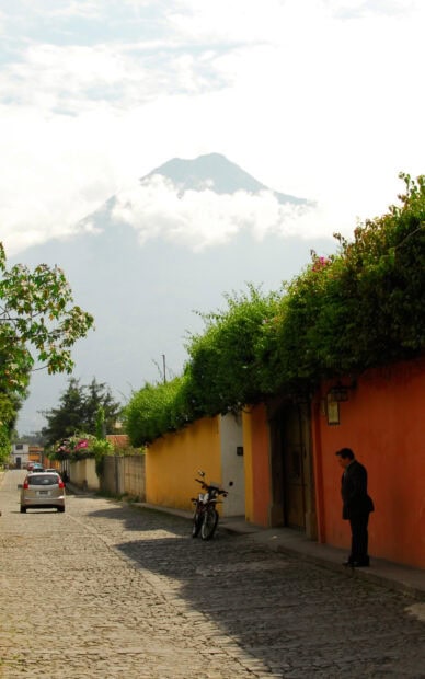 A quiet street in Guatemala with lush greenery and a mountain in the background