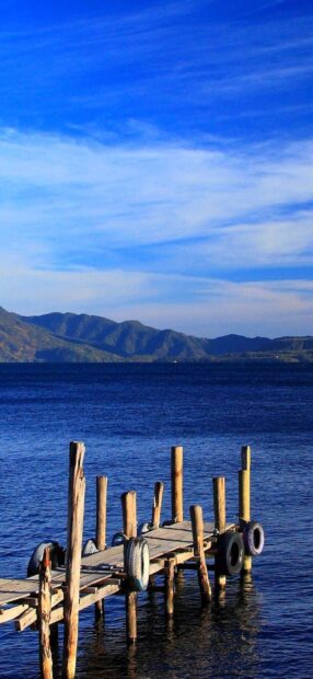 Wooden pier by the lake with mountains in Guatemala scenery