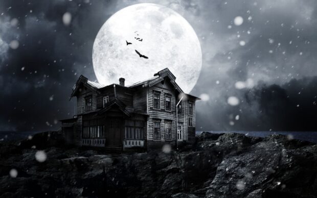 Haunted house surrounded by rocks under a full moon with bats flying nearby
