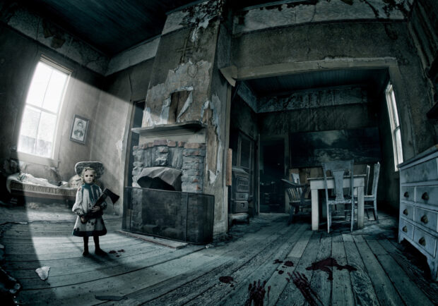 A creepy child holding an ax stands in a haunted house with bloody footprints on wooden floor